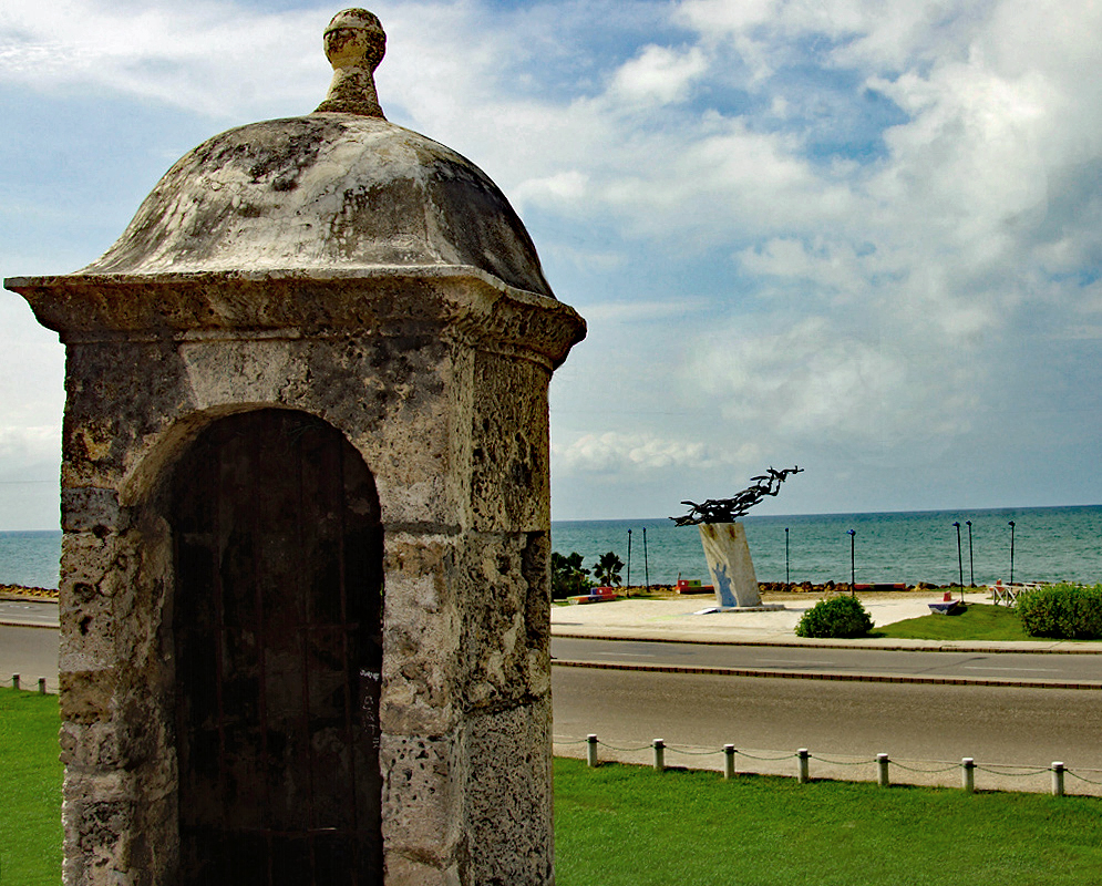 Old fort guard-tower in front of a statue of seagulls overlooking the blue ocean